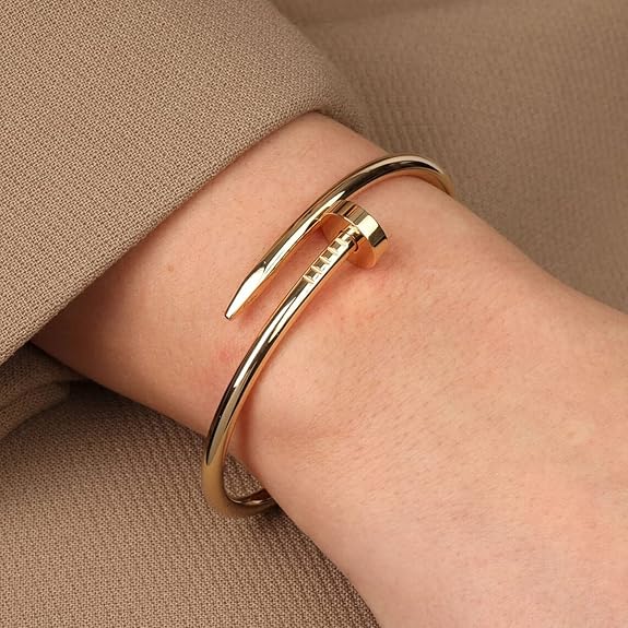 Gold bangle on a wrist with a neutral background