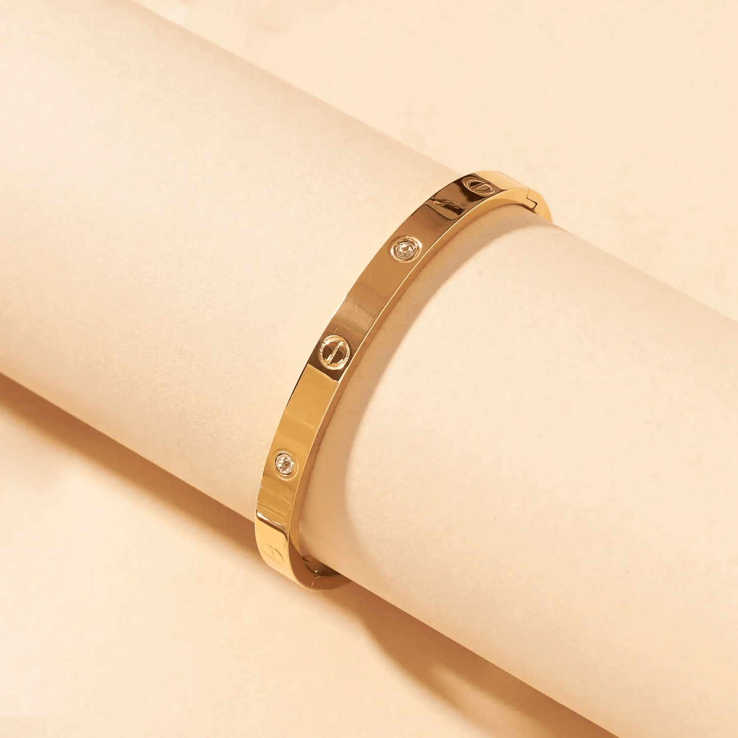 Gold bracelet with diamond accents on a beige background