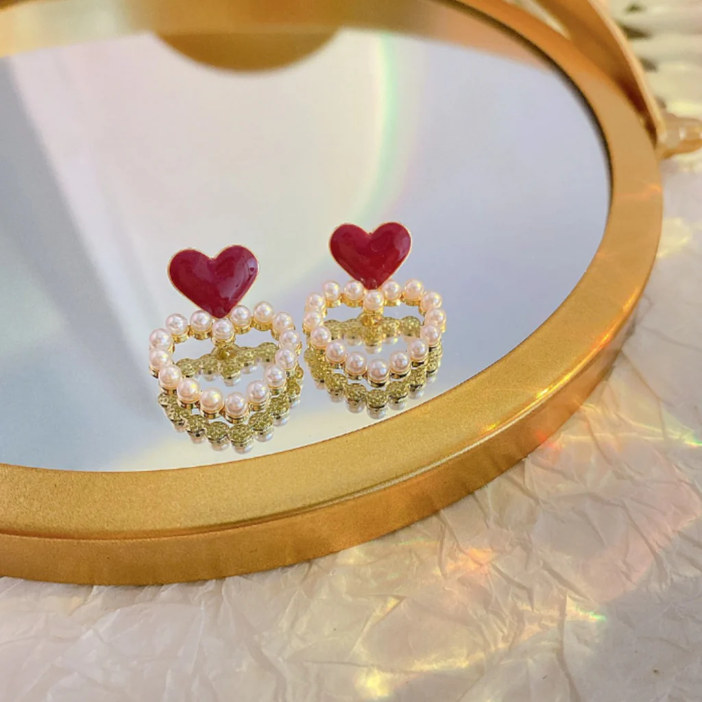 Heart-shaped earrings with pearl details on a round mirror