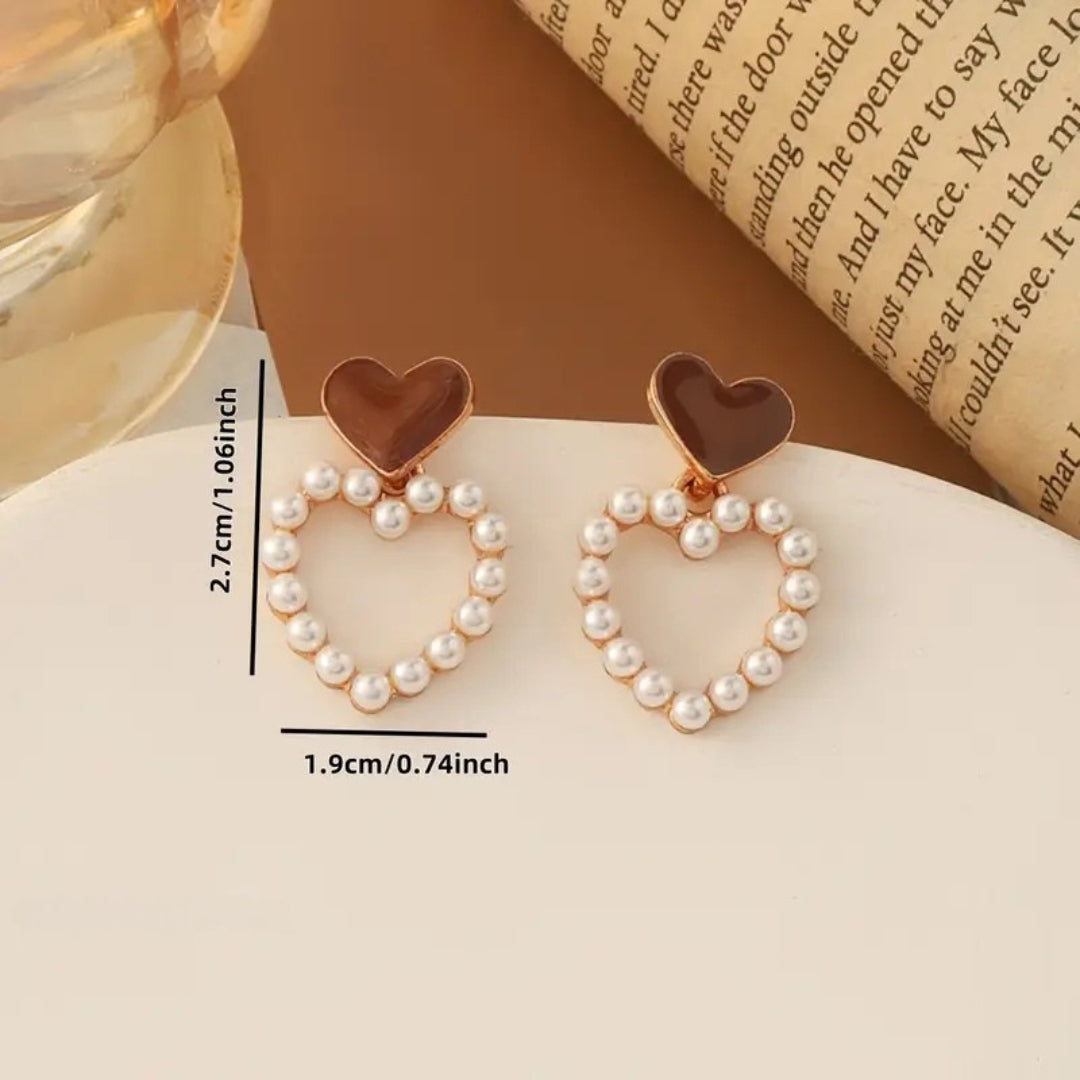 Heart-shaped earrings with pearl details on a white surface, measurement labels included.