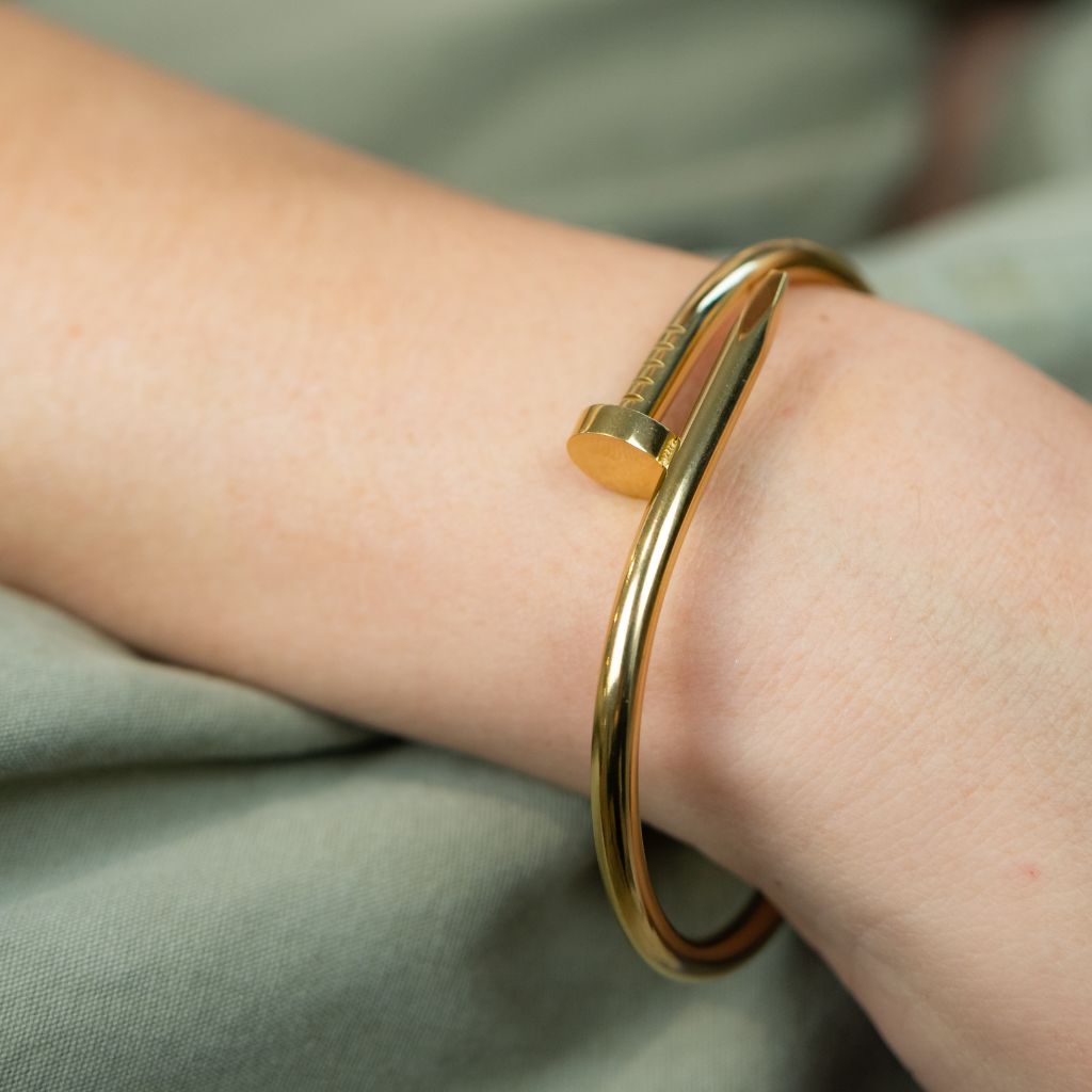 Gold bracelet on a wrist with a soft green fabric background