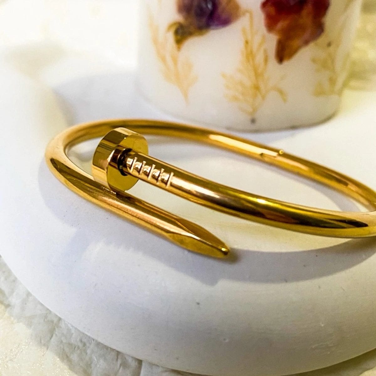Gold bangle on a white surface with a blurred background