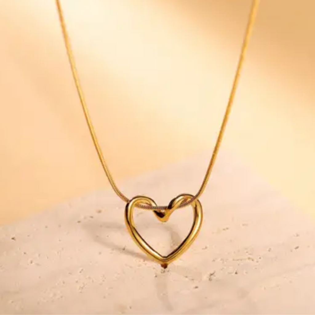 Gold heart-shaped necklace on a beige background