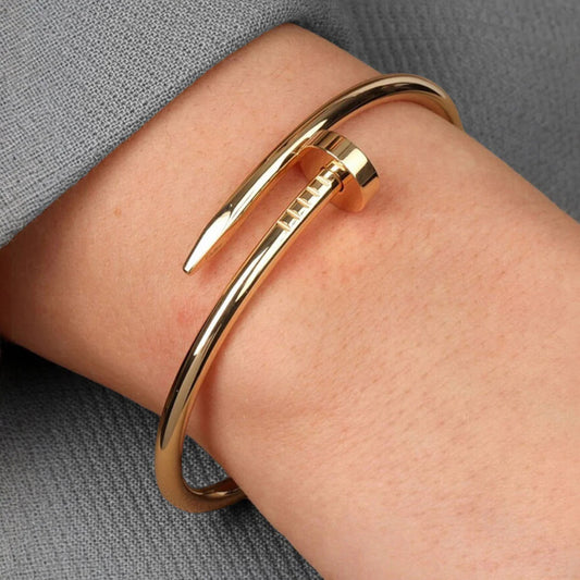 Gold bangle on a wrist with a gray background