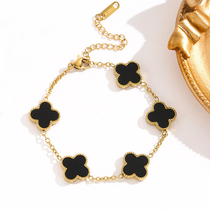 Gold bracelet with black clover-shaped charms on a white background