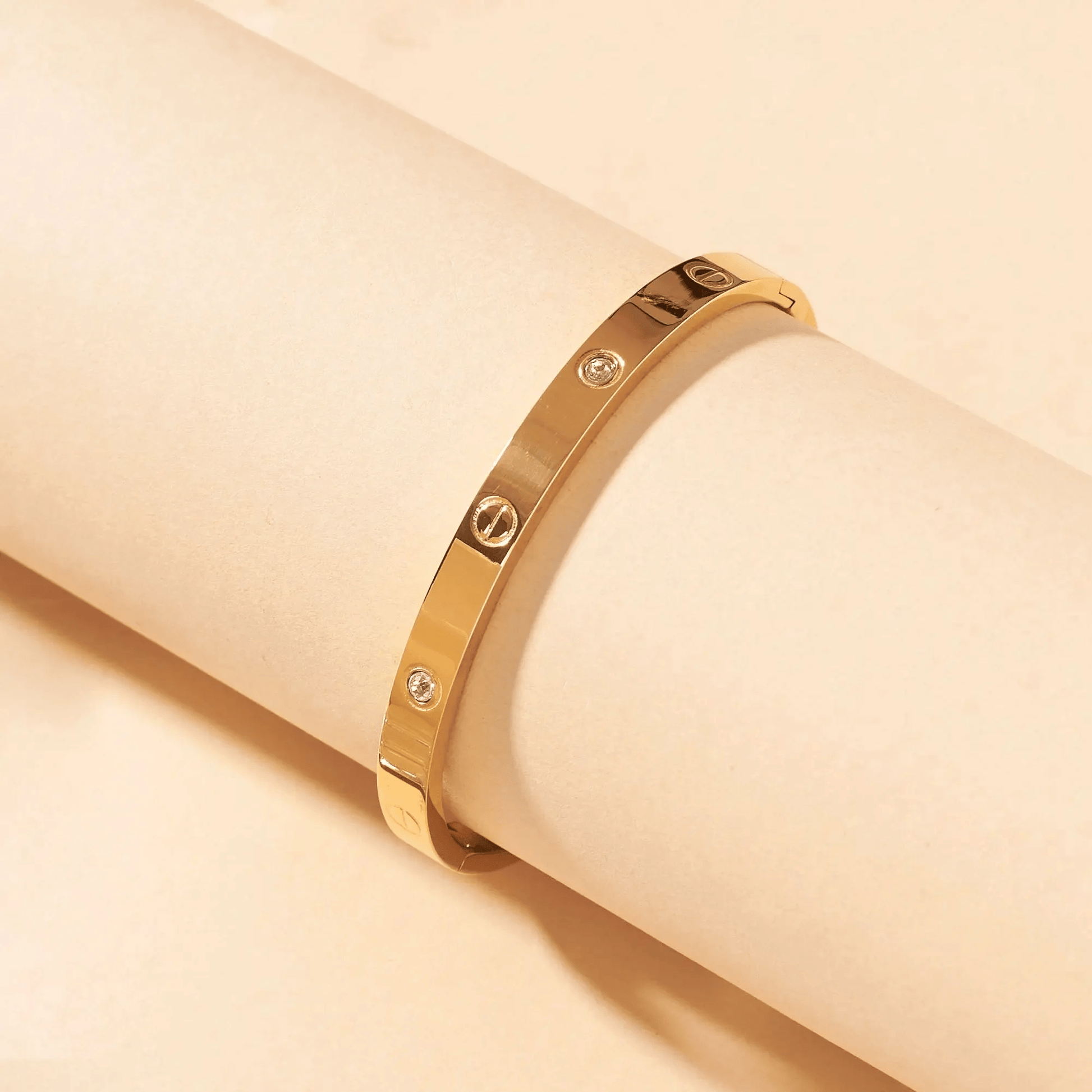 Gold bracelet with diamond accents on a beige background