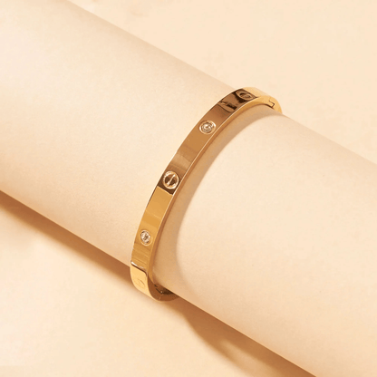 Gold bracelet with diamond accents on a beige background