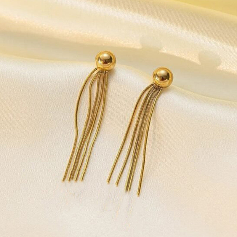 Gold tassel earrings on a light beige fabric background
