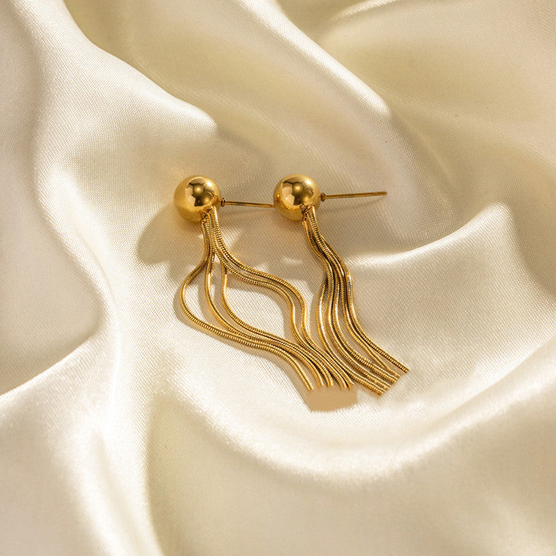 Gold tassel earrings on a beige fabric background