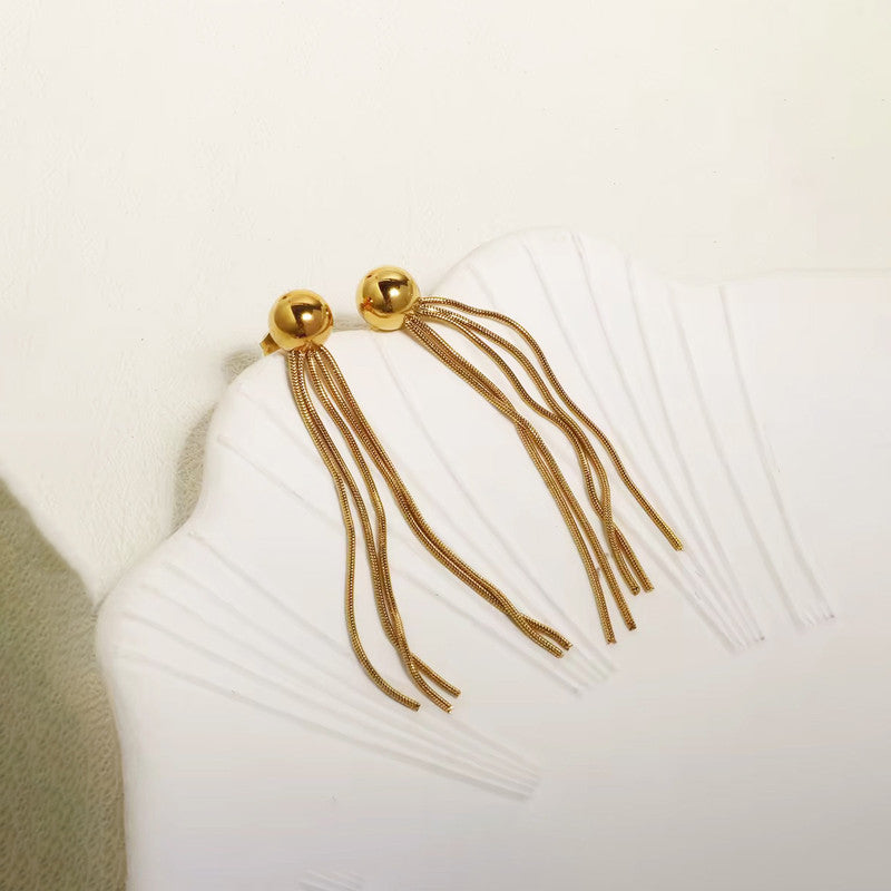 Gold tassel earrings on a white pillow