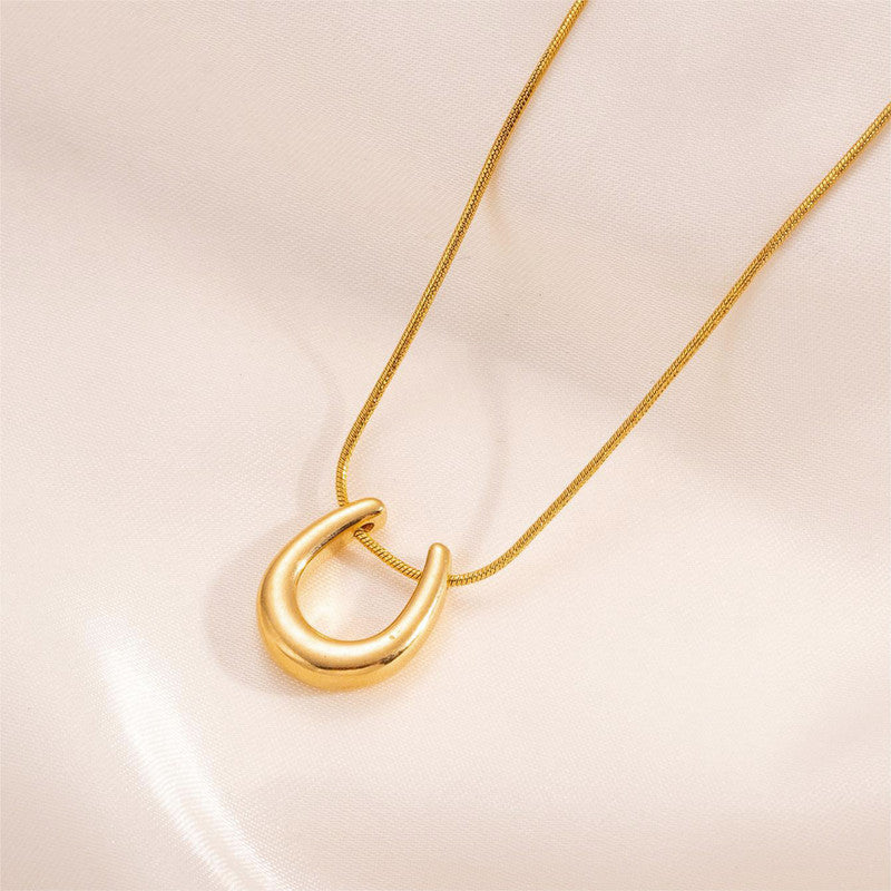 Gold necklace with a unique pendant on a light pink background