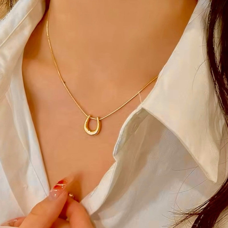 Gold necklace with a small pendant worn by a person in a white shirt.
