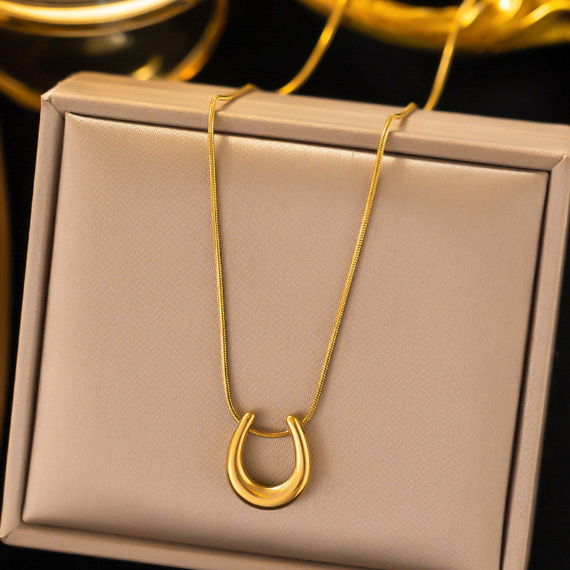Gold necklace with a unique pendant on a beige jewelry box