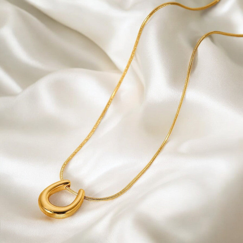 Gold necklace with a unique pendant on a white fabric background