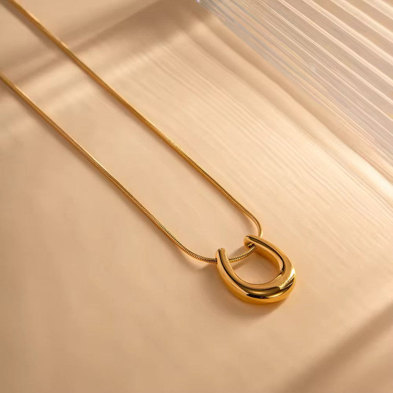 Gold necklace with a unique pendant on a beige surface