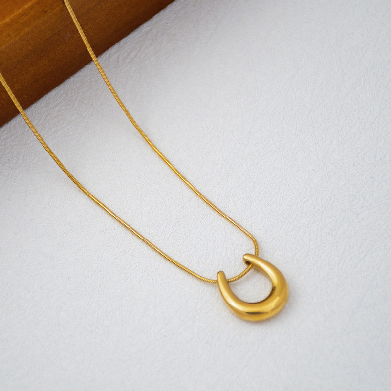 Gold necklace with a unique pendant on a white surface