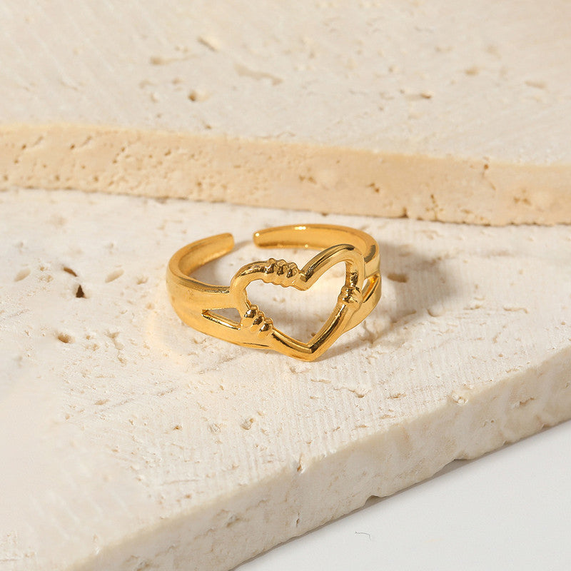 Gold heart-shaped ring on a textured beige surface
