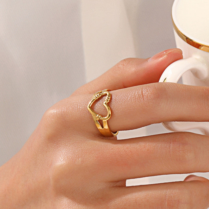 Gold heart-shaped ring on a hand with a blurred background
