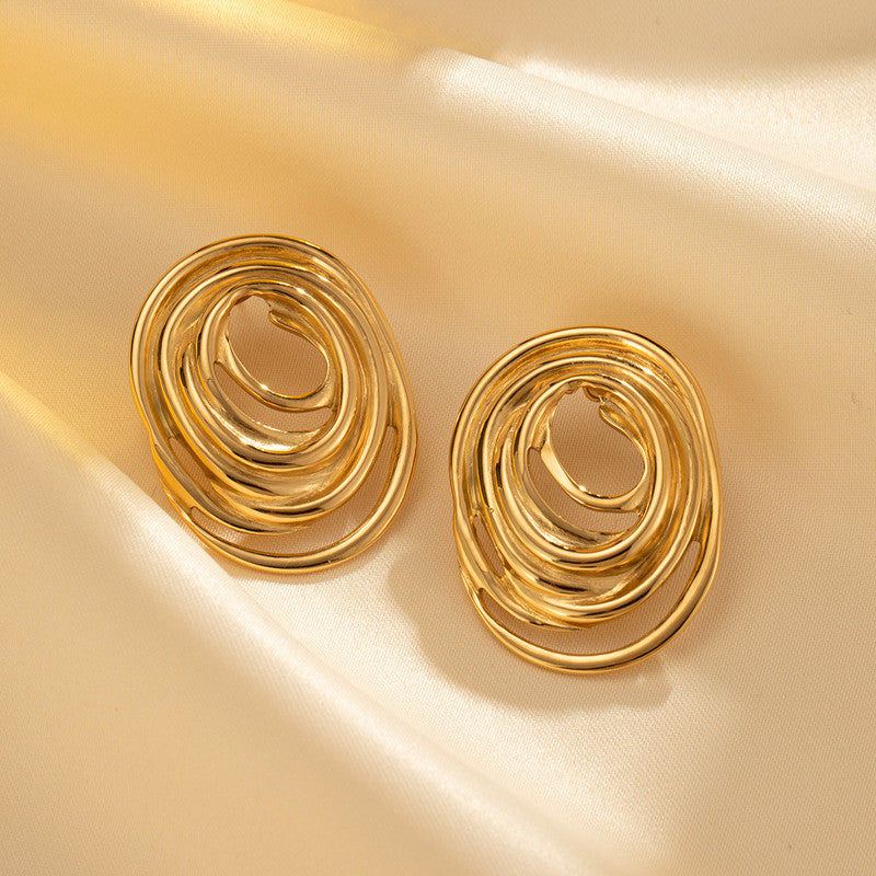 Pair of gold spiral earrings on a beige background