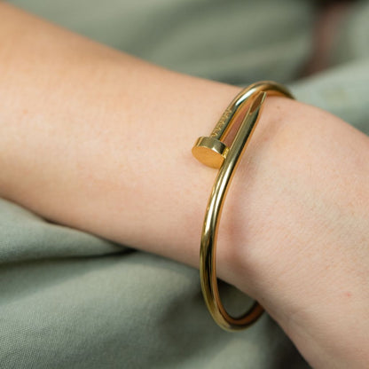 Gold bracelet on a wrist with a soft green fabric background