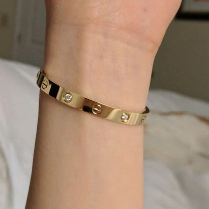 Gold bracelet with diamonds on a wrist against a neutral background